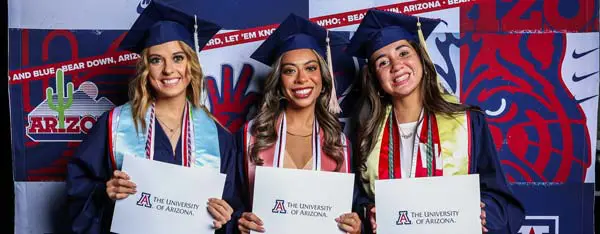 Graduates holding holding papers with school logo